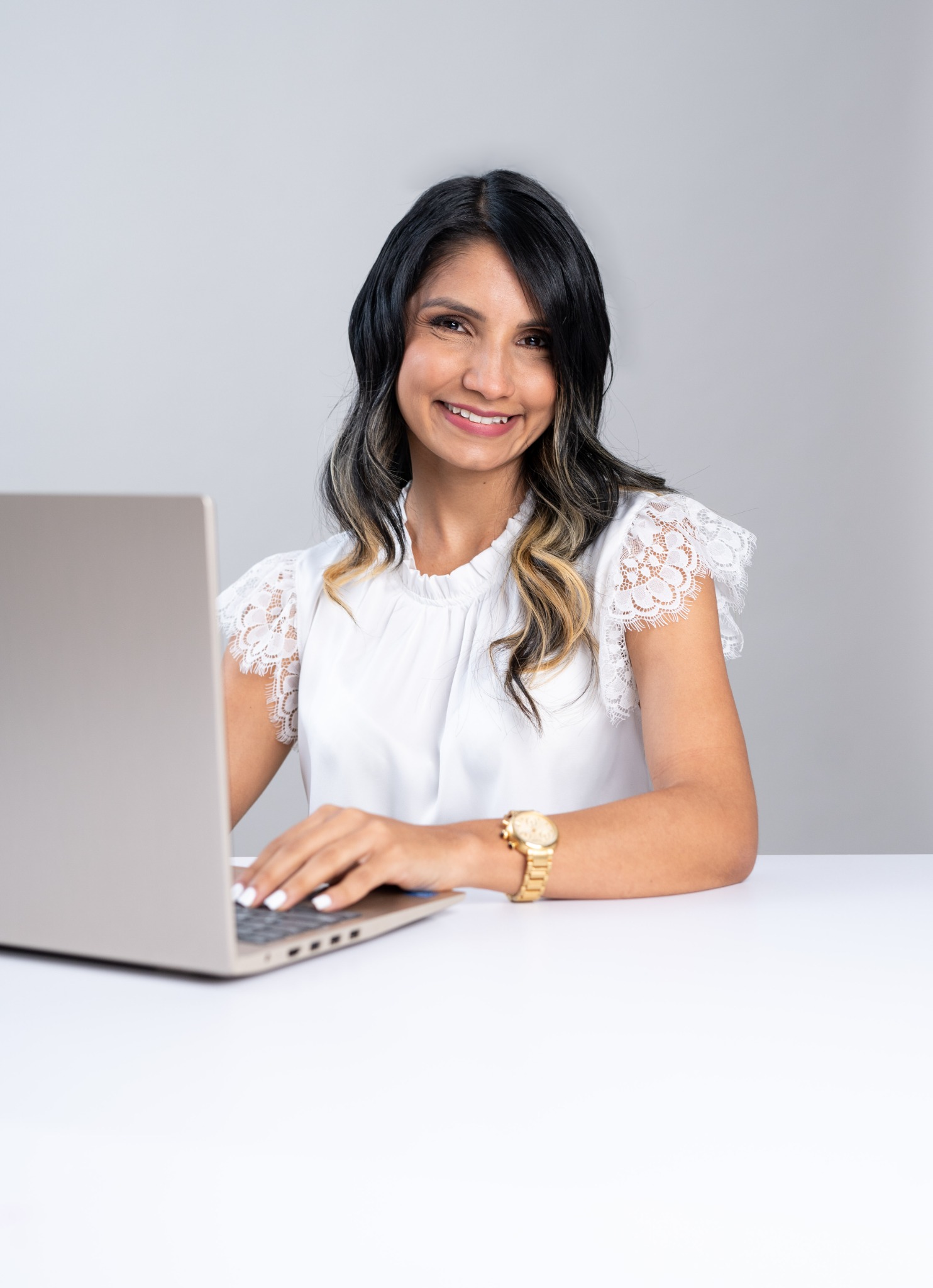 Mariángel Álvarez, con camisa blanca, sonríe junto a su computadora